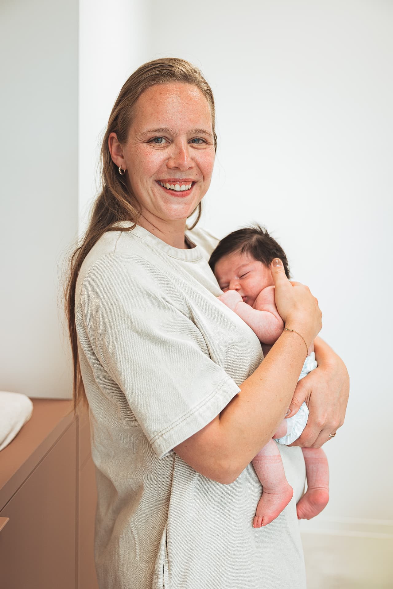 Kelsey Christiaens glimlacht met een pasgeboren baby in haar armen